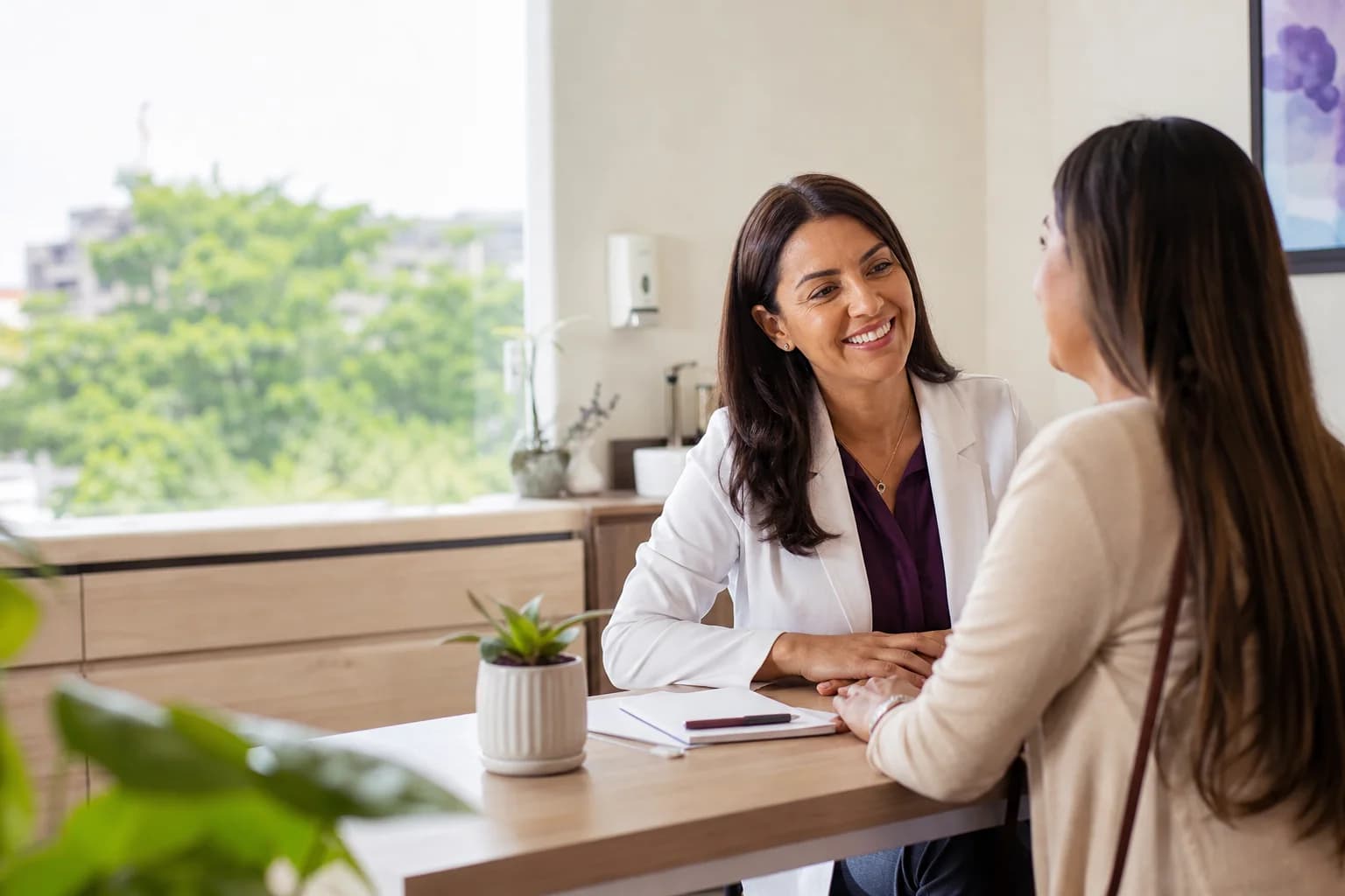 Doctora atendiendo a una paciente mientras su agenda digital sigue disponible